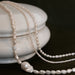 Pearl necklace draped over a white ceramic container on a dark background