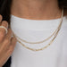 Close-up of a person wearing pearl and gold necklaces with a white shirt.